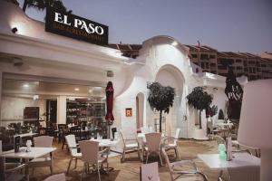 a restaurant with white tables and chairs in a building at Castle Harbour Official in Los Cristianos