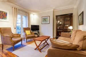 een woonkamer met een bank en stoelen en een tv bij Greeter-Appartement Haussmannien avec balcon in Parijs