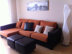 a living room with an orange couch and a white vase at CORMORANT SUITE, sea terrace & pools in La Manga del Mar Menor