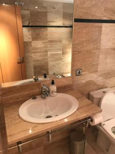 a bathroom with a sink and a toilet and a mirror at Luxury apartment set in Doña Julia Golf Course in Casares