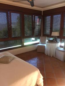 a bedroom with a bed and a table and windows at villaquinta in La Herradura