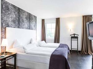 a bedroom with a white bed and a tv at Hotel Künstlerquartier Seezeichen in Ahrenshoop