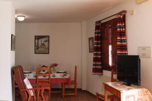 a dining room with a table and a television at Apartamentos Rurales Rosendo: "El Laurel" in Capileira