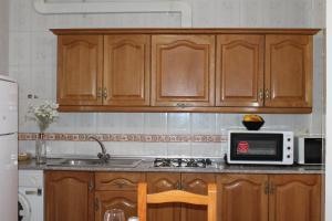 a kitchen with wooden cabinets and a microwave at Apartamentos Rurales Rosendo: "El Laurel" in Capileira