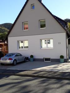 a white house with a car parked in the driveway at Ferienwohnungen am Köhlerhang Bad Lauterberg im Harz in Bad Lauterberg