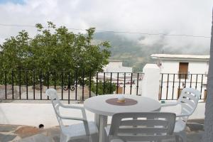einen weißen Tisch und Stühle auf einem Balkon mit Aussicht in der Unterkunft Apartamentos Rurales Rosendo: "Flor de Lys" in Capileira