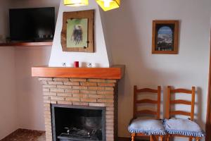 ein Wohnzimmer mit 2 Stühlen und einem Kamin in der Unterkunft Apartamentos Rurales Rosendo: "Flor de Lys" in Capileira
