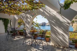 a patio with tables and chairs and a view of the water at Agios Pavlos Hotel in Agios Pavlos