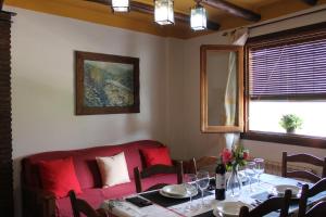 a dining room with a table and a red couch at Apartamentos Rurales Rosendo: "La Pimienta" in Capileira