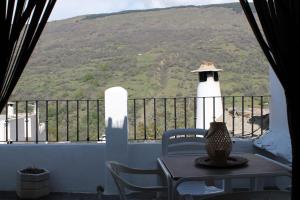 a table and chairs on a balcony with a lighthouse at Apartamentos Rurales Rosendo: "La Pimienta" in Capileira