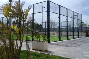 una pista de tenis con valla y plantas en Playa Mar, en Torre del Mar