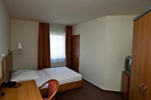 1 dormitorio con cama, mesa y TV en Hotel Manu, en Paderborn