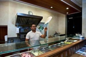 Un uomo in piedi dietro un bancone in una cucina di Hotel Manu a Paderborn