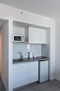 una cucina bianca con lavandino e forno a microonde di Netanya SeaView ApartHotel a Netanya