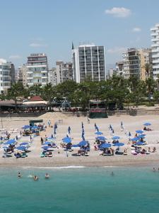 a beach with chairs and umbrellas and people in the water at Olbia Hotel in Antalya