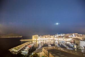 Una ciudad de noche con barcos en un puerto en Dubrovnik Sunset Apartments en Dubrovnik