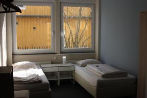 a room with two beds and a table and two windows at Ahoi-Gästehaus in Hamburg