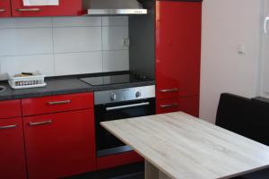 a kitchen with red cabinets and a stove and a table at Ahoi-Gästehaus in Hamburg