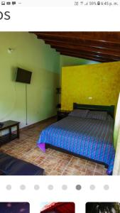1 dormitorio con cama y pared amarilla en Alojamiento Campestre Cabañas Mirador Ingrumá Riosucio Caldas en Ruiosucio