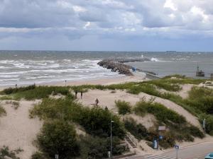a beach with people walking on the sand and the ocean at Apartment Ventspils in Ventspils