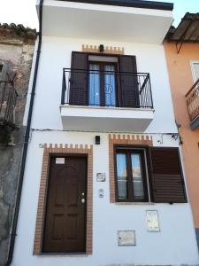 a white building with a balcony and a door at Casa Vacanza "A Due Passi" in Paravati