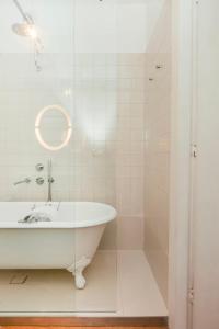 un bagno bianco con vasca e specchio di Rosa Et Al Townhouse a Porto