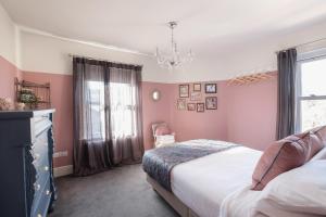 Schlafzimmer mit rosa Wänden, einem Bett und einem Kronleuchter in der Unterkunft The Victorian Post House - Central Frome in Frome