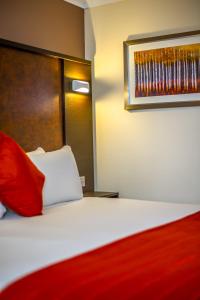 キングズ・リンにあるDragonfly Hotel King's Lynnの赤い枕付きのベッドが備わるホテルルームです。