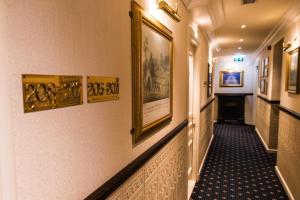 un couloir avec des peintures et des photos sur les murs dans l'établissement Boutique Hotel De Doelen, à Groningue