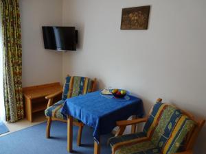 een kamer met een tafel en stoelen en een televisie bij Pension Wolfsegg in Kirchberg in Tirol