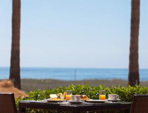 a table with food and drinks on it with the ocean in the background at Dom Pedro Lagos in Lagos