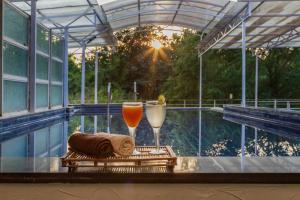 two glasses of orange juice and towels on a table next to a swimming pool at SaffronStays Bellini, Karjat in Kalamb