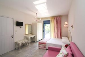 1 dormitorio con 1 cama y 1 sofá rosa en Golden Blue Studios, en Chrysi Ammoudia