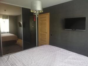 um quarto com uma cama e uma televisão na parede em Justinos Apartamentai Panevėžyje em Panevėžys