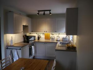 a kitchen with white cabinets and a wooden table at Scafell View Apartment, Wasdale, Lake District, Cumbria in Nether Wasdale
