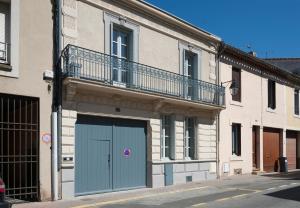 un bâtiment avec une porte de garage bleue et un balcon dans l'établissement Maison Borrel, à Carcassonne
