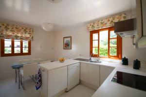 アルクーディアにあるBarcares Granの白いキャビネット、シンク、窓付きのキッチン