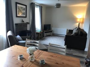 ein Wohnzimmer mit einem Holztisch mit Blumen darauf in der Unterkunft Scafell View Apartment, Wasdale, Lake District, Cumbria in Nether Wasdale