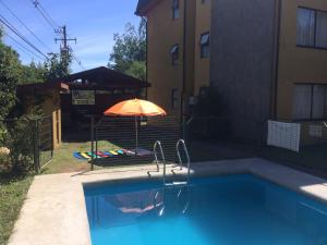 una piscina con sombrilla junto a un edificio en Departamento Pucon, en Pucón