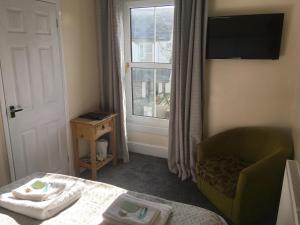 a room with a bed and a chair and a window at Mair's in Bridgend