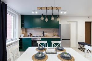 a kitchen with green cabinets and a table with stools at Pušyno apartamentai in Anykščiai