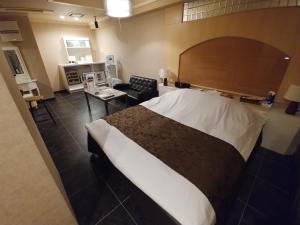 a bedroom with a large bed and a living room at Hotel Allure (Adult Only) in Nagoya