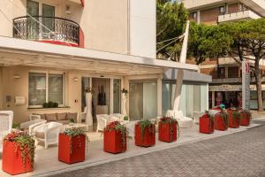 une rangée de récipients rouges avec des plantes sur un bâtiment dans l'établissement Baia del Mar Beach Boutique Hotel, à Lido di Jesolo