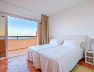 a bedroom with a bed with a view of the ocean at Dom Pedro Lagos in Lagos