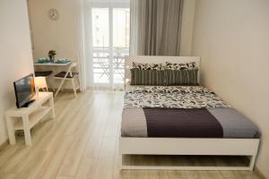 Un dormitorio con una cama, un escritorio y un televisor. en Apartamenty Zamulkowa 4TWO, en Katowice