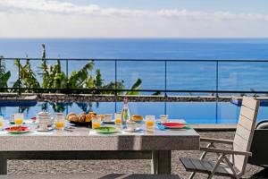 阿科卡希塔的住宿－OurMadeira - Grayci's House, contemporary，一张桌子,上面摆放着食品和饮料,并享有海景