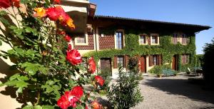 un bâtiment avec des fleurs rouges devant lui dans l'établissement Cascina Delle Rose, à Barbaresco