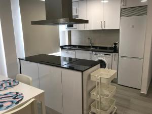 a kitchen with white cabinets and a sink and a dishwasher at Apartament L'Alba in Tossa de Mar