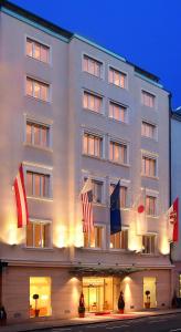 a large white building with a flag on top of it at Hotel IMLAUER & Bräu in Salzburg