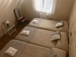 une chambre avec deux lits et une chaise et une fenêtre dans l'établissement Apartamento Rurales El Mirador de Carboneras, à Carboneras de Guadazaón